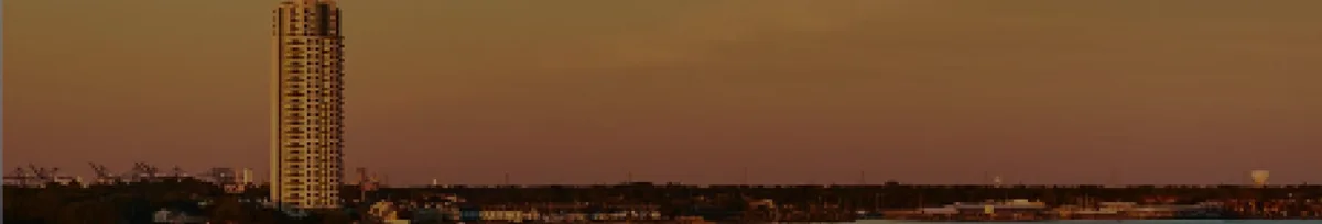 A high-rise residential tower in Clear Lake silhouetted against a sunset skyline